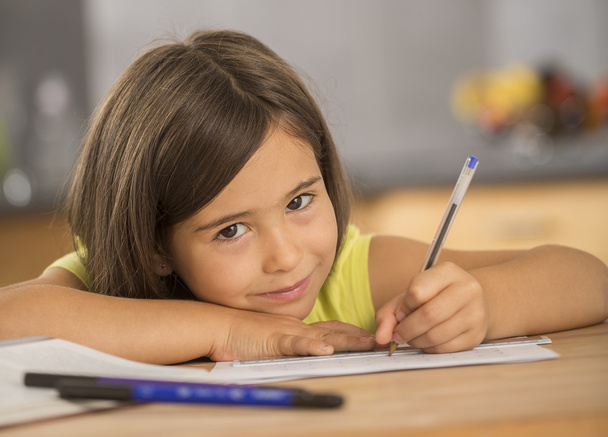 Portrait of little girl doing homework ar table - Fotoğraf, Görsel
