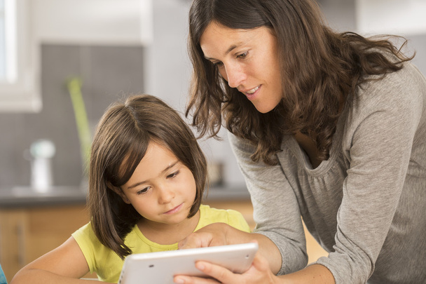 mother and daughter doing homework with a tablet - Photo, Image