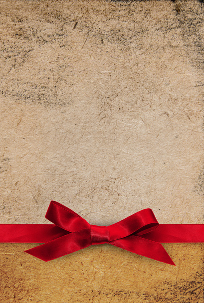 Red ribbon bow on gold textured paper - Foto, Bild