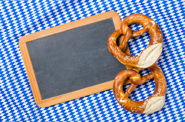 Empty blackboard with pretzels on a bavarian diamond pattern - Photo, Image
