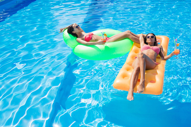 Girls resting on air mattress in swimming pool  - Photo, Image