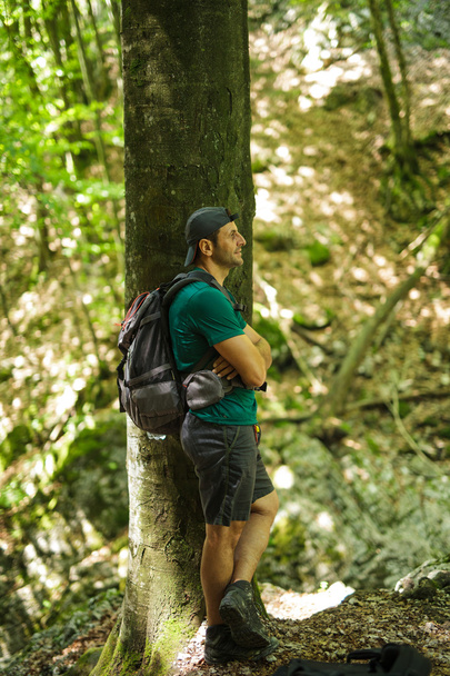 man with backpack leaning against a tree - Foto, imagen