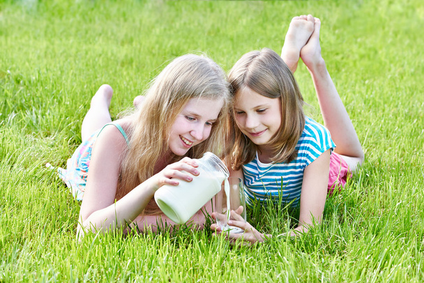 Two girls pours milk in sunny meadow - Zdjęcie, obraz