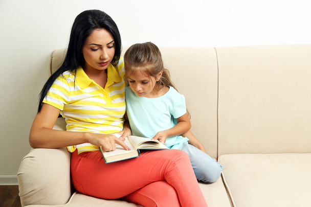 girl reading book with mother - Zdjęcie, obraz