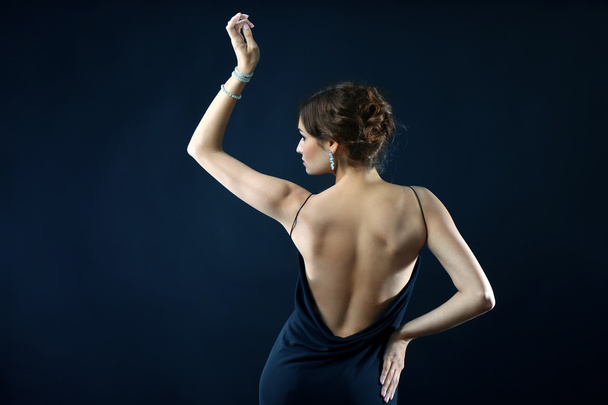 Pretty woman with bare back on dark background - Photo, image