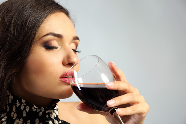 Portré, fiatal nő pohár vörös bor, a szürke háttér - Fotó, kép