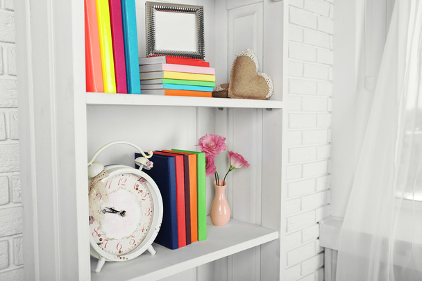 Books and decor on shelves - Φωτογραφία, εικόνα
