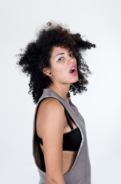 Hispanic brunette model with messy hair wearing grey sleeveless shirt looking unhappy into camera from profile angle, mugshot concept - Φωτογραφία, εικόνα