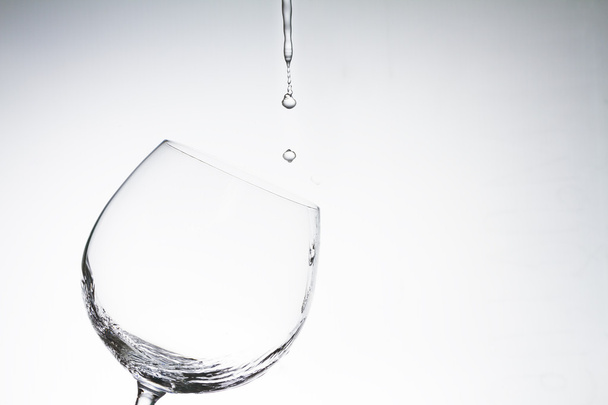 Water drop into wine glass on white background - 写真・画像