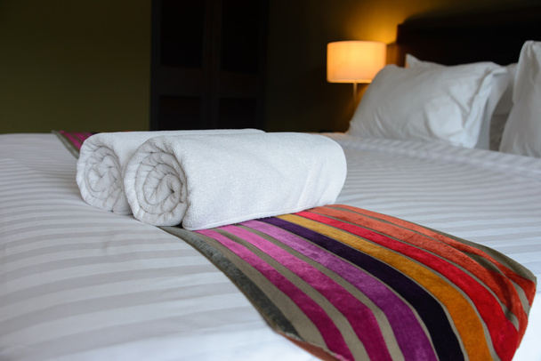 Λευκή πετσέτα στο κρεβάτι στο υπνοδωμάτιο της χαλάρωσης του πολυτελούς ξενοδοχείου μπουτίκ - Φωτογραφία, εικόνα