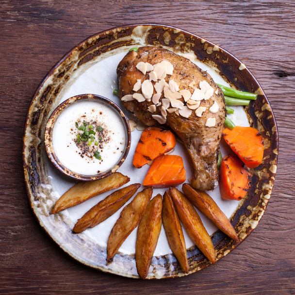жареные куриные барабанные палочки с картофельным клином, морковь на тарелке
 - Фото, изображение