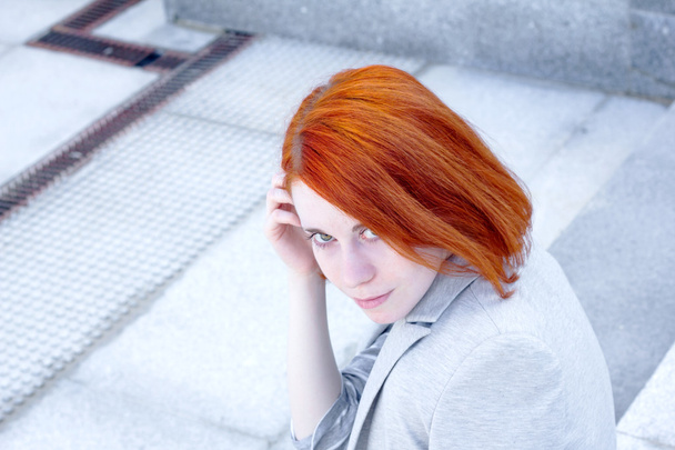 Portrait of redhead business woman with smile sitting outside on the stairs - Fotoğraf, Görsel