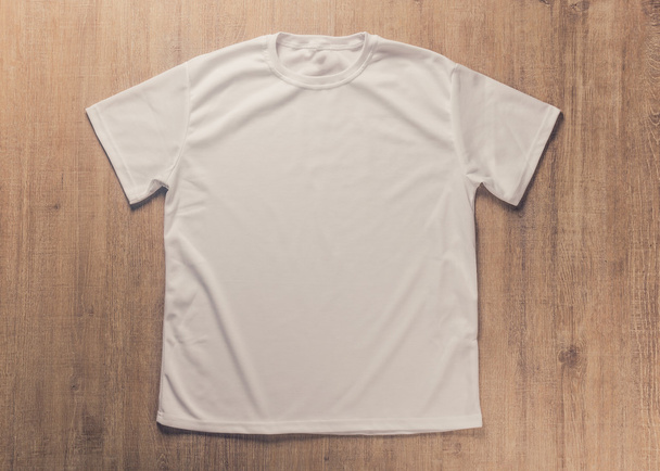White blank t-shirt on dark wood desk - Φωτογραφία, εικόνα