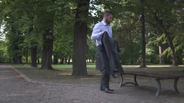 Businessman sits on bench in park and starts working with documents. - Footage, Video