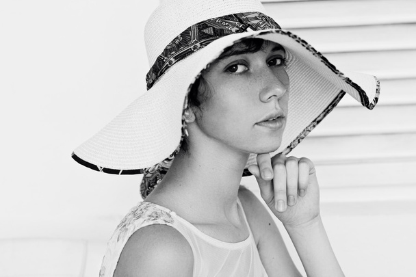 Beautiful young girl with beauty skin and a thoughtful look in the big white hat - Photo, Image
