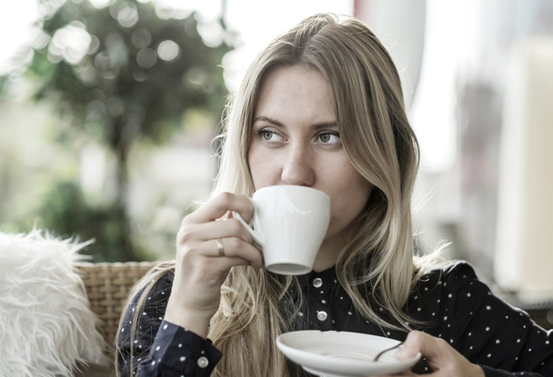 blonde female drink coffee in cafe - Фото, зображення