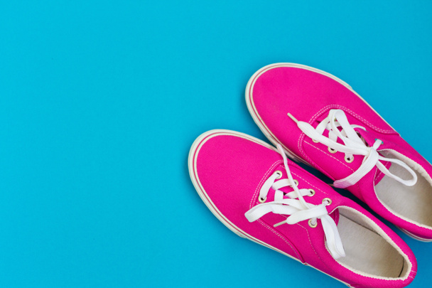 Zapatillas de deporte rosa con cordones blancos en un azul
 - Foto, imagen