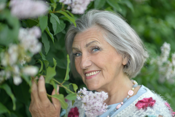 Older woman with flowers - Foto, afbeelding