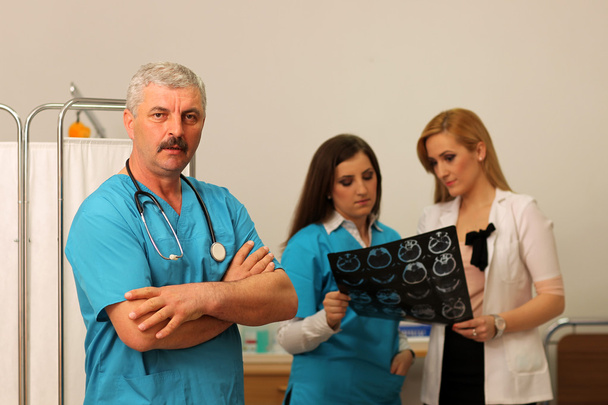 médico com duas enfermeiras verificando radiografia
 - Foto, Imagem