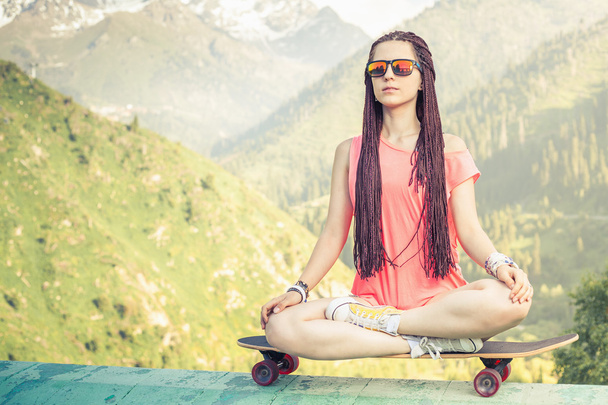 Hipster fashion girl doing yoga, relaxing on skateboard at mountain - Φωτογραφία, εικόνα