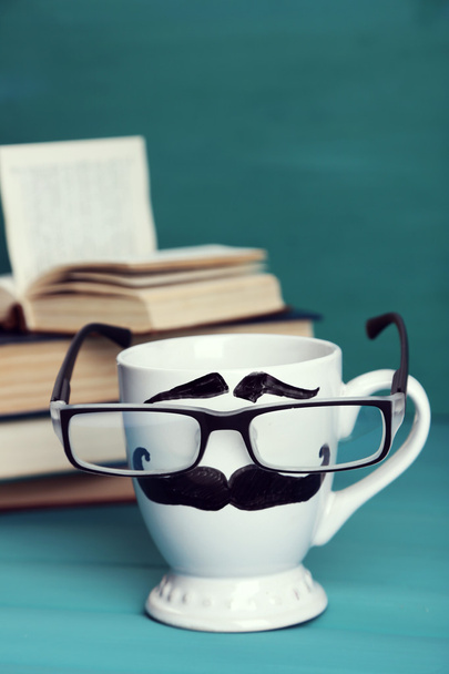 Books and cup with mustache on colorful background - Φωτογραφία, εικόνα