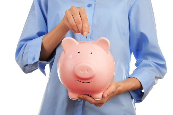 Female hands putting coin into pink piggy bank, closeup - Zdjęcie, obraz