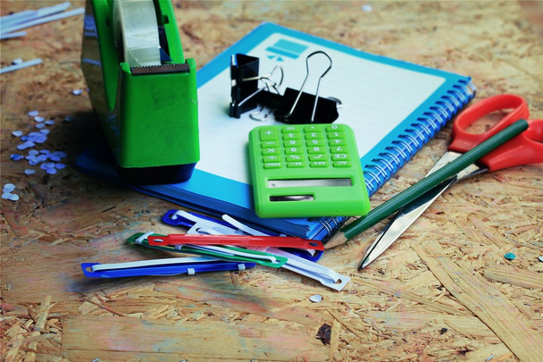 Meng boek en rekenmachine, nietmachine, tape, papier punch, potlood - Foto, afbeelding
