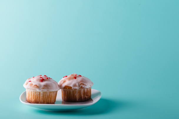Colorful muffin on saucer. Aqua color plain background - 写真・画像