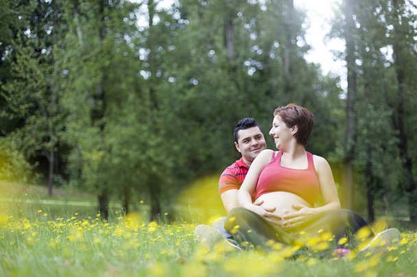 Young pregnant couple hugging in nature - Foto, afbeelding