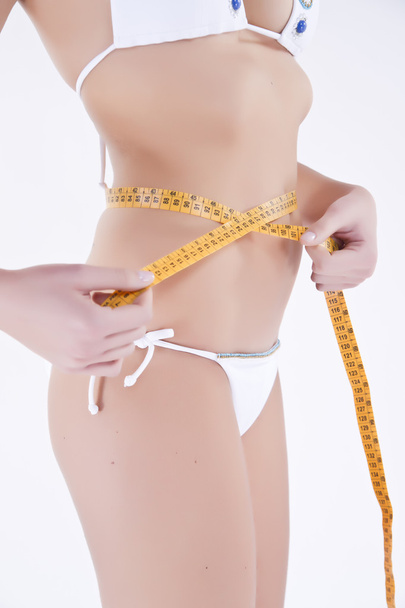 A woman with a measuring tape around her waist. - Фото, зображення