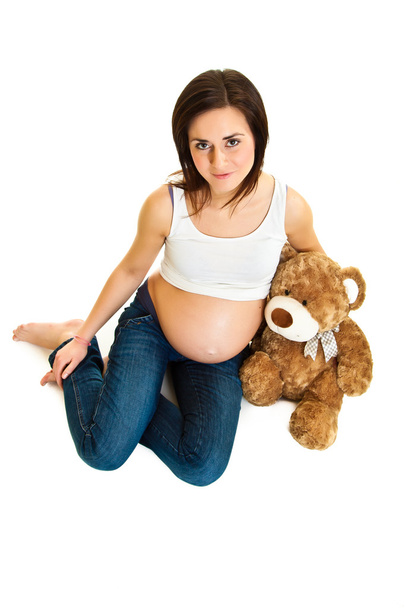 Brunette pregnant woman with teddy bear isolated on white - Foto, Imagen