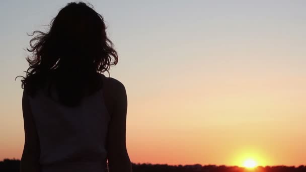 Молода жінка дивиться на дивовижний помаранчевий захід сонця на горизонті, думаючи про майбутнє
 - Кадри, відео