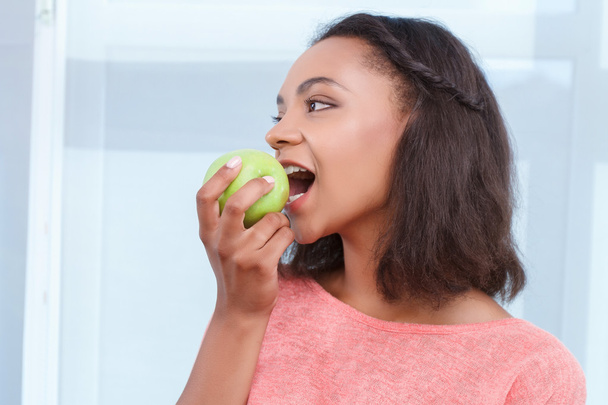 Mulatto lady eating fresh apple - Фото, изображение