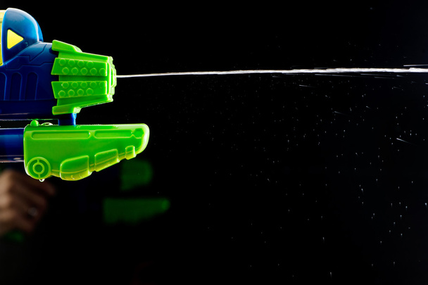 Water spuit pistool pistool shootinh water op zwart - Foto, afbeelding