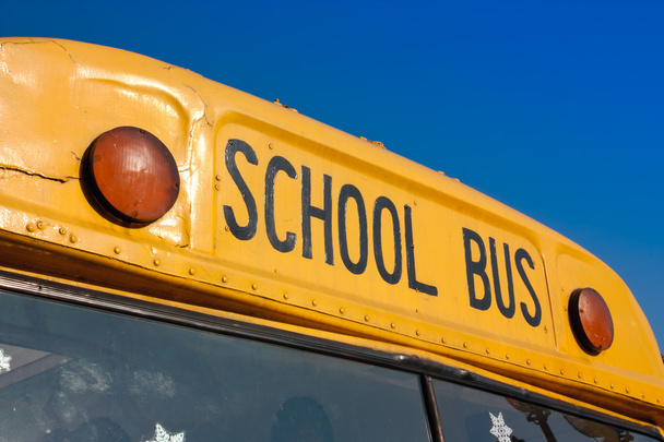 Keltaisen koulubussin edessä sinistä taivasta vasten
 - Valokuva, kuva