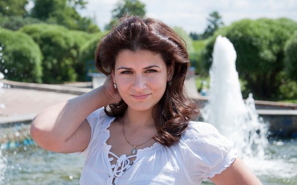 Young dark-haired girl at the fountain in the park - Photo, image