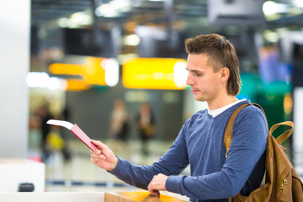 Mooie man met paspoorten en boarding passeert bij de receptie in airport - Foto, afbeelding