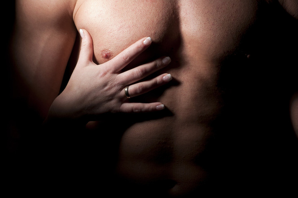 Female hand on the man's muscular chest. - Foto, afbeelding