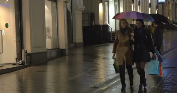 Lányok, akik egy sétát, és beszélni vásárlás után az esti városban - Felvétel, videó