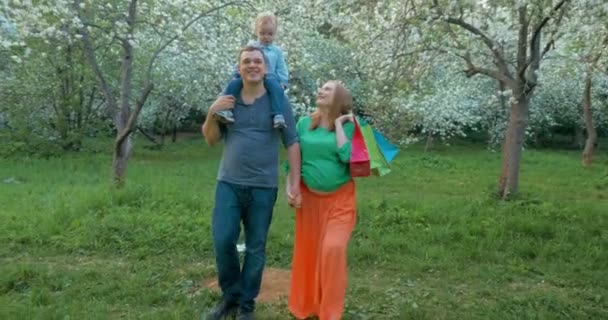 Onnellinen perhe lapsen kanssa kävelemässä kukoistavassa puistossa
 - Materiaali, video