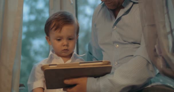 Otec a malý syn používají tabletový počítač doma - Záběry, video