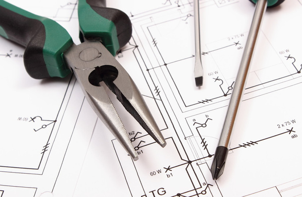 Alicate de metal e chave de fenda no desenho de construção elétrica da casa
 - Foto, Imagem