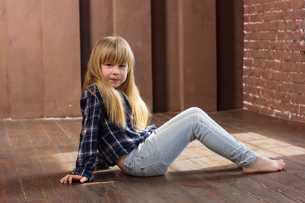 Mädchen 6 Jahre alt in Jeans auf dem Boden sitzend - Foto, Bild