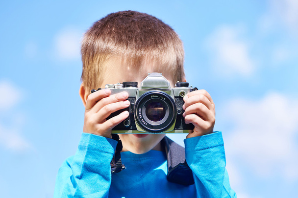 Niño pequeño con cámara SLR retro en el cielo azul
 - Foto, Imagen