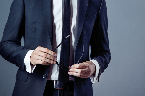 ο άνθρωπος στο κοστούμι σε γκρι φόντο, τα χέρια closeup - Φωτογραφία, εικόνα