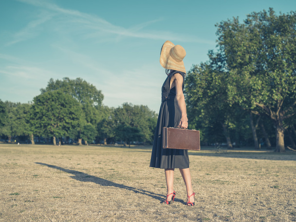 Elegancki młoda kobieta z teczki stojący w parku - Zdjęcie, obraz