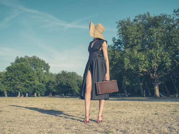 Elegante jonge vrouw met werkmap staan in park - Foto, afbeelding