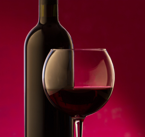 A glass and bottle of red wine  - Фото, изображение