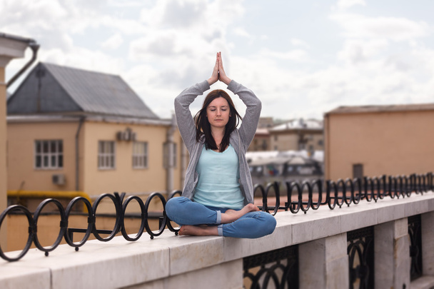 Relaxed young woman in a yoga pose on the parapet - Photo, Image