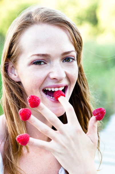 woman eating raspberries off her fingers outdoors - Фото, изображение